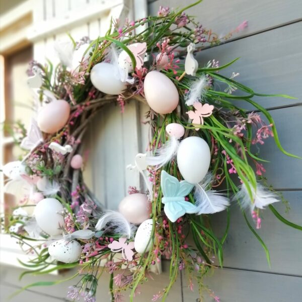 hand made wianek dekoracyjny z różowymi kwiatami jajkami pisankami i ozdobnymi turkusowymi motylami
